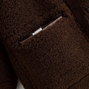 Gros plan sur la texture en daim marron et les détails de poche de la veste femme