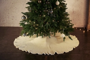 Detailed texture of ivory cable-knit Christmas tree skirt in a cozy holiday home setting