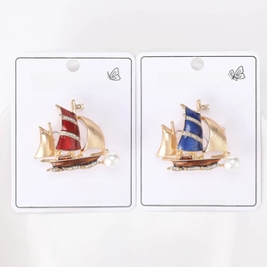 Macro shot of red and blue enamel sailboat brooches with pearls and rhinestone accents