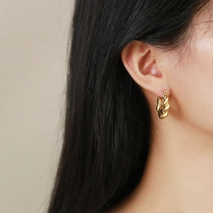 Golden twisted rope hoop earrings with a textured vintage design on a female model