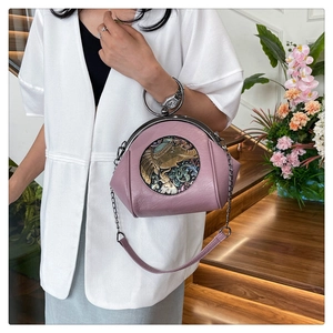 Detail of mauve shell bag featuring vintage elephant relief and stylish metal handle