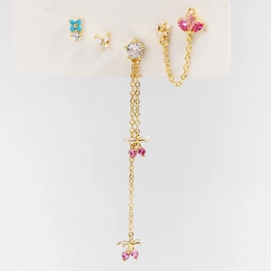 Detailed close-up of gold ear studs set with pink and blue cubic zirconia on white card