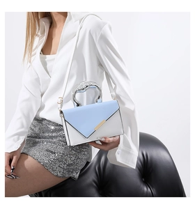 Detail of artistic silver metal handle and gold buckle on a blue and white handbag