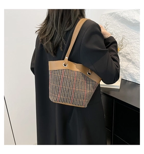 Classic brown leather and plaid bucket bag shown on shoulder for a stylish winter look