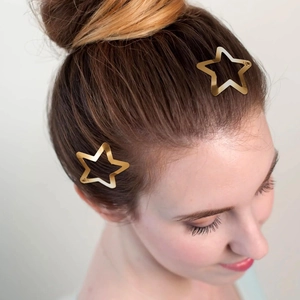 Close-up of golden star-shaped hair clips on hair with polished metallic finish