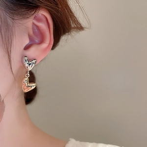 Close-up of a model wearing minimalist gold and silver contrast heart-shaped earrings