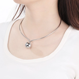Close-up of a silver hollow sphere pendant necklace worn by a model on a clean background