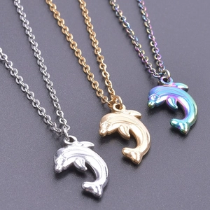 Three dolphin pendants in silver, gold, and rainbow finishes on a dark textured background