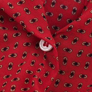 Vue macro détaillée du tissu imprimé rouge avec motifs de chaîne noir-or et bouton blanc