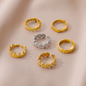 Detailed view of six adjustable gold and silver rings with seashell and crown designs