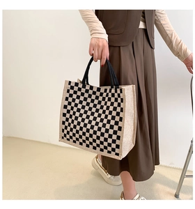 Close-up of checkerboard jute tote bag with black handles and natural flax texture