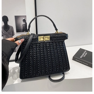 Detail of black woven handbag featuring golden rotating clasp and removable strap
