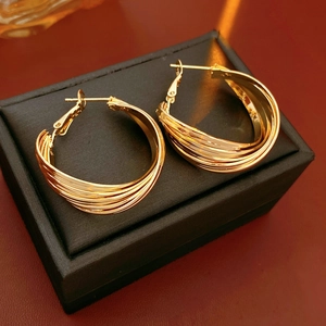 Detailed close-up of golden multi-layer twisted hoop earrings in a black jewelry box