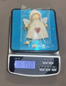 Detail view of handmade wool angel ornament weighing 15.0g on a digital scale