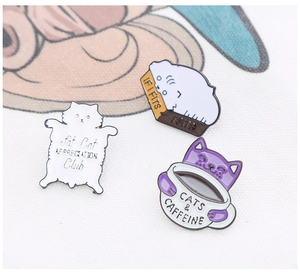Detailed shot of three creative enamel cat pins including Fat Cat Club and coffee themes
