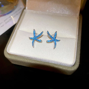 Dettaglio macro di orecchini a lobo a stella marina blu con inserti scintillanti in box