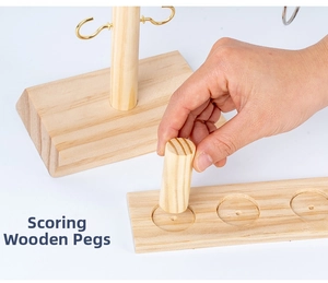 Detail of hand placing scoring peg into wooden base for ring toss tabletop game