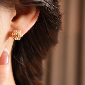 Gros plan sur des boucles d'oreilles fleur en perles dorées avec strass sur un mannequin