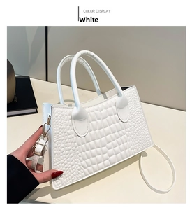 Close-up of white crocodile pattern PU handbag with cylindrical handles and metal buckle