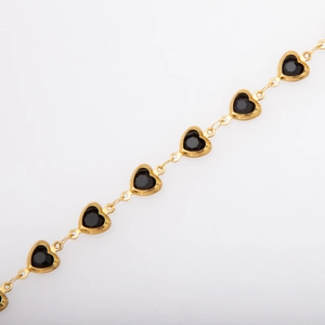 Macro shot of gold-plated heart-shaped links with black stone inlays on a dainty chain