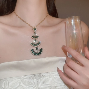 Detail of four-tier fan-shaped gold pendant necklace with green pear gemstones