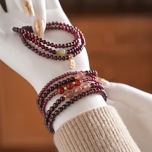 Garnet and red agate multi-layer beaded bracelet with gold Fu tag on model wrist