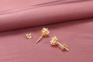 Macro detail of gold six-prong S925 silver stud earrings with round cubic zirconia stones