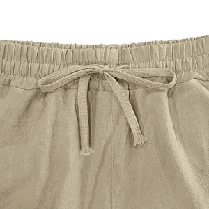 Close-up of khaki linen shorts with elastic drawstring waist and breathable fabric texture