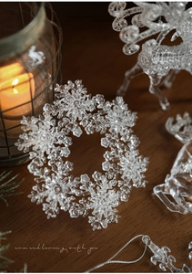 Macro shot of a transparent acrylic snowflake ornament on a dark wooden table with warm lighting