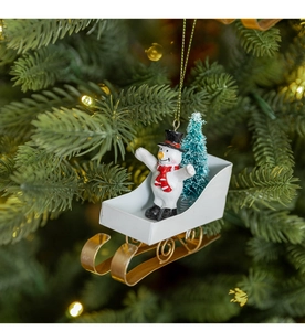 Christmas snowman in metal sleigh ornament hanging on a festive tree branch