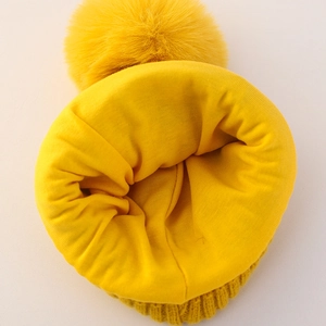 Vista detallada de gorro de invierno amarillo para bebé con forro polar y pompón