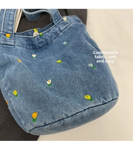 Detailaufnahme der blauen Jeans-Beuteltasche mit bunter Blumenstickerei und feinen Nähten