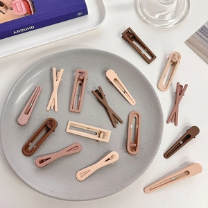 Flat lay of matte brown, beige and pink seamless hair clips on a speckled tray