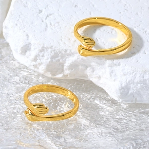 Detailed view of two gold hug rings with hand shape on stone and glass base