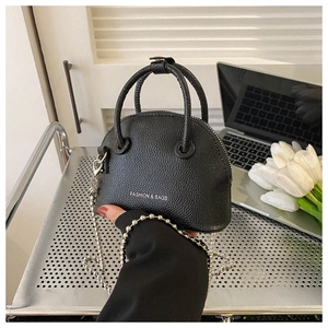 Detail of black lychee grain shell bag with silver chain strap in a modern office setting