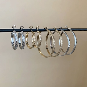 Detailed view of gold and silver hoop earrings with twill texture in multiple sizes