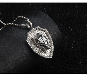Detailed close-up of shield-shaped wolf pendant with sparkling rhinestones on leather background