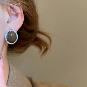 Close-up of retro acrylic leopard print heart earring worn on earlobe with silver frame