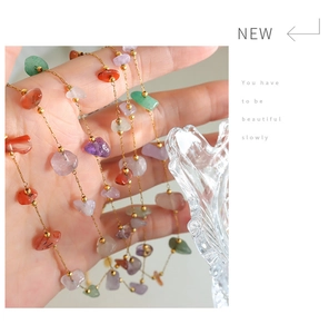 Detail of colorful natural stone pendant on gold chain necklace held by hand