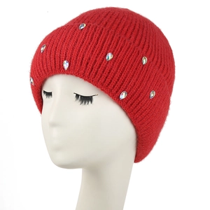 Gros plan sur le bonnet en tricot rouge épais orné de strass brillants sur fond blanc