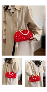 Détail d'une pochette en dentelle florale rouge avec perles et chaîne en métal doré