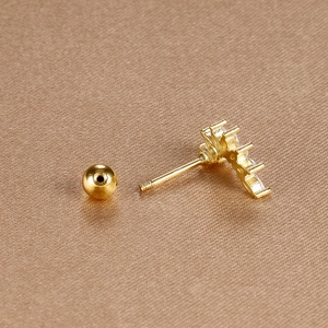 Macro view of gold leaf stud earring with curved row of diamonds and screw-back closure