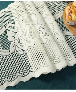 Close-up of cream lace table runner showing intricate floral hollow patterns and texture
