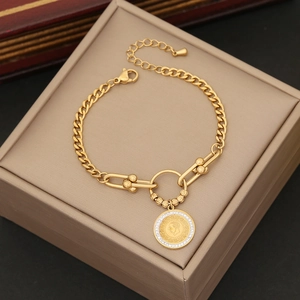 Detailed close-up of golden stainless steel curb chain bracelet with coin pendant and zircons