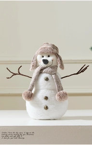 Detail of plush snowman decoration with plaid pilot hat and branch arms for Christmas