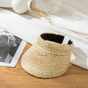 Detailed close-up of straw visor with scalloped edges and sweatband on wooden desk