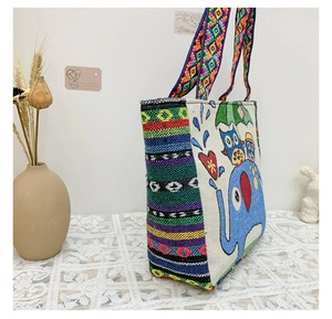 Close-up of bohemian woven tote bag featuring colorful elephant and owl patterns