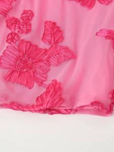 Détail du tissu en maille rose avec broderie florale 3D et ourlet ondulé sur une robe