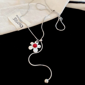 Detailed shot of silver snake chain necklace with a red flower pendant on black background
