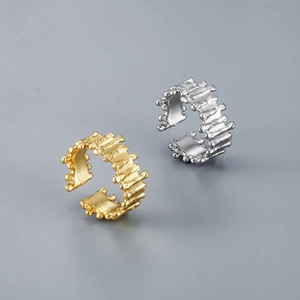 Close-up of golden and silver open rings with irregular molten lava texture design